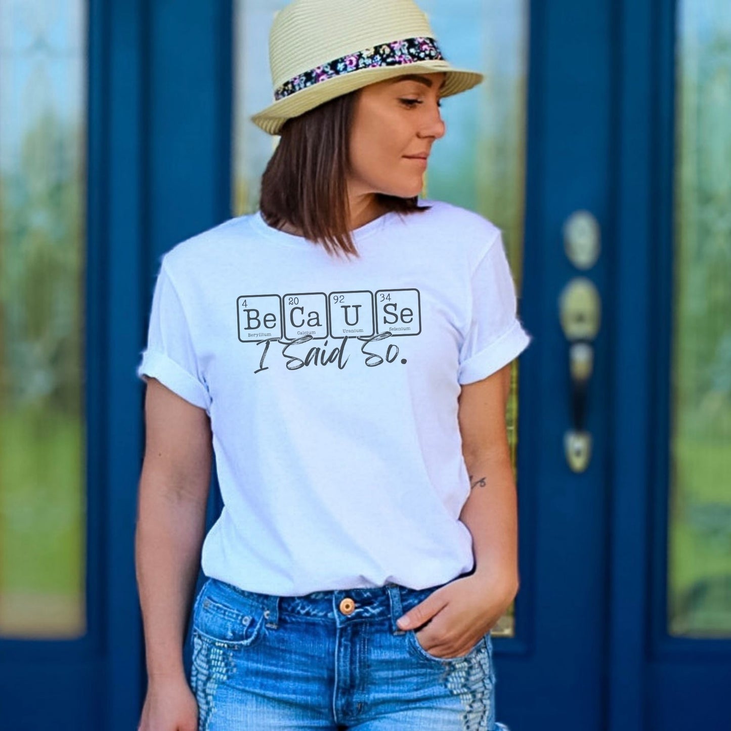 a woman wearing a white t - shirt with periodic table design for the text that says "because I said so", wearing blue jeans and a straw hat