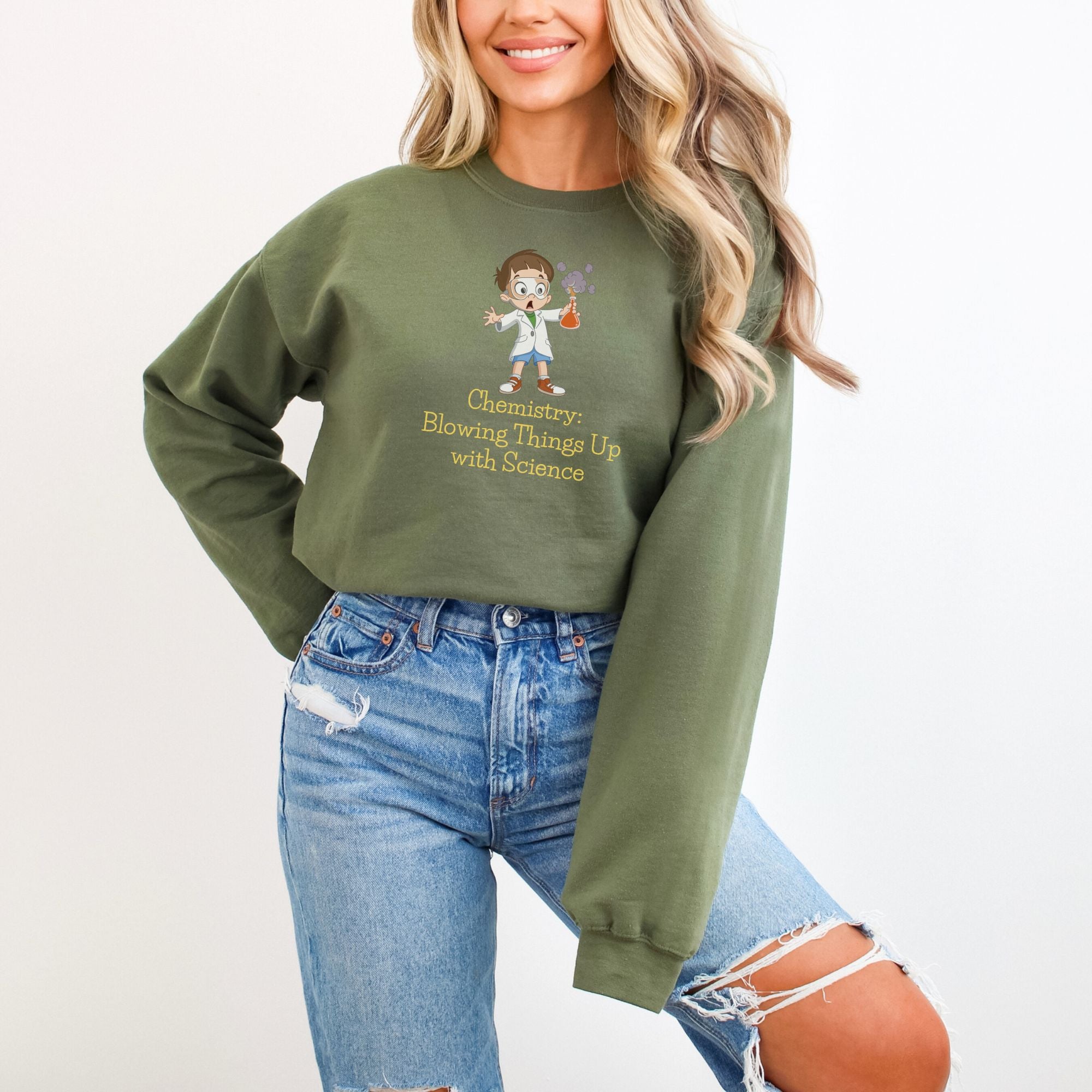 smiling woman wearing a military green sweater with a design that says "chemistry: blowing things up with science"