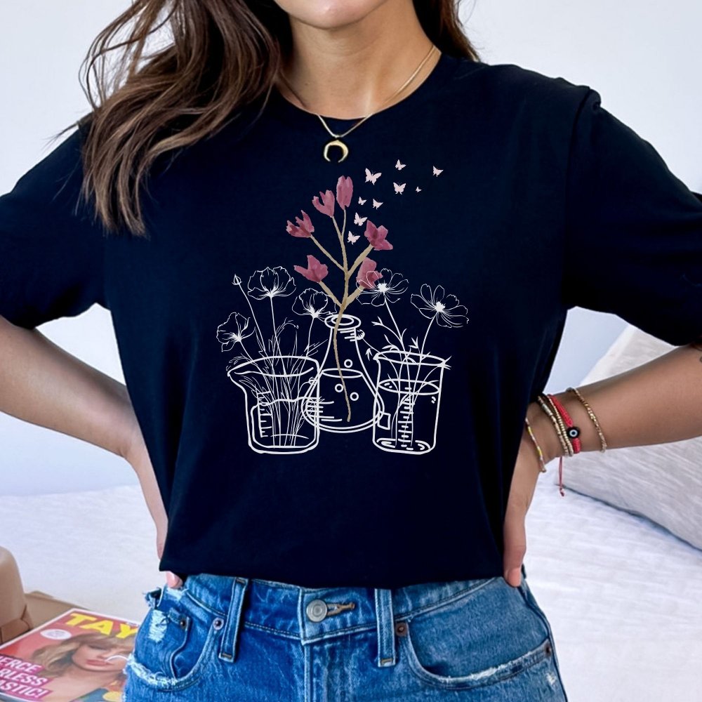 Black t-shirt featuring a unique floral design with flowers in laboratory beakers and flasks, perfect for lab technicians who love a mix of science and nature. This casual tee combines a minimalist science theme with a stylish, comfortable fit.