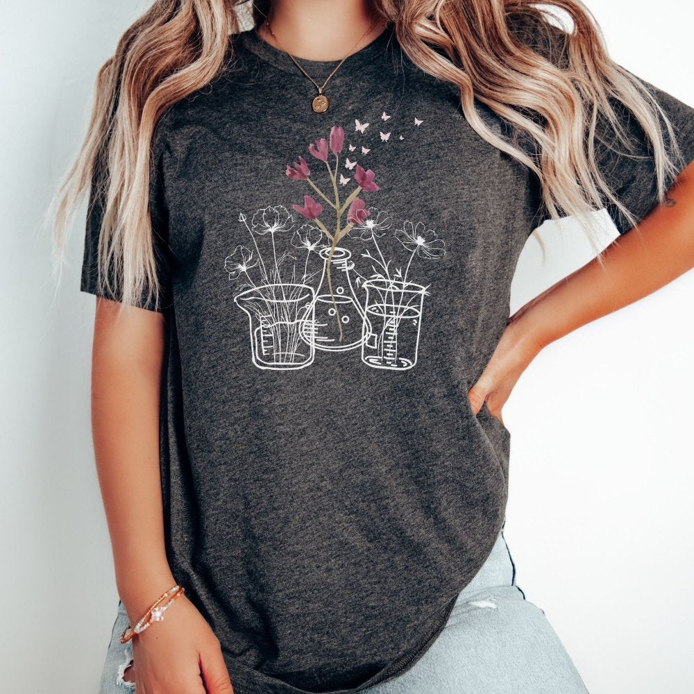 Dark gray heather t-shirt featuring a floral science design with flowers growing from lab beakers and flasks, perfect for lab technicians who love combining science and nature in a casual, comfortable style.