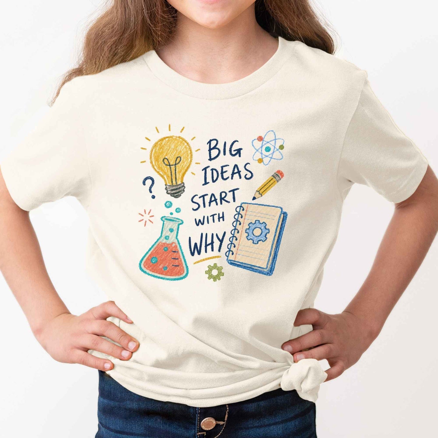 A child wearing a cream-colored graphic t-shirt with a colorful science-themed design that reads 'BIG IDEAS START WITH WHY' alongside a light bulb, beaker, pencil, and notebook. The child is also wearing blue jeans against a clean white background.
