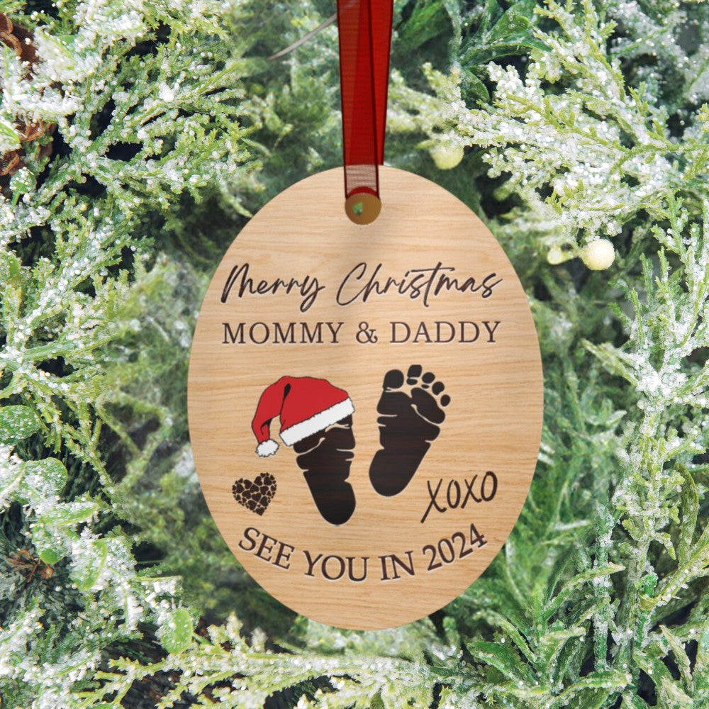 a wooden ornament with a baby's feet and a santa hat on