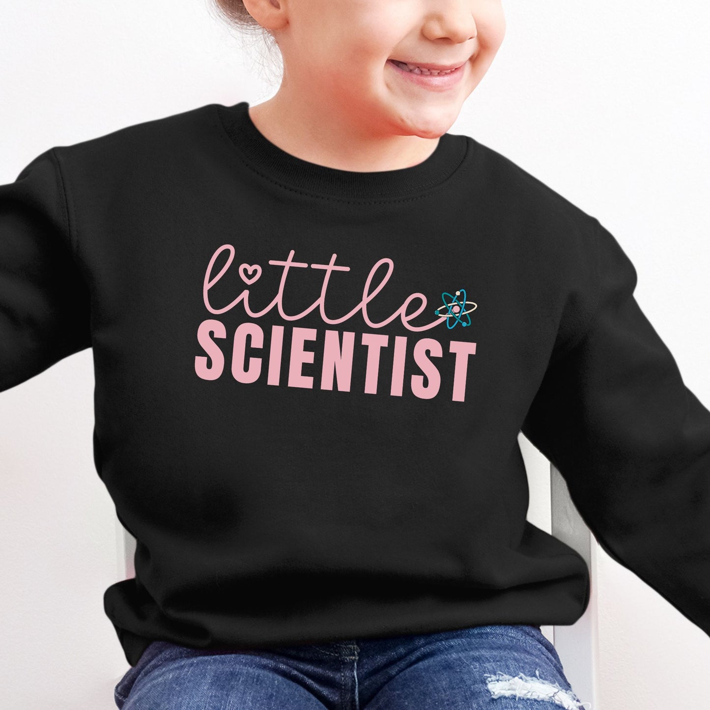 a little girl wearing a black sweatshirt that says little scientist
